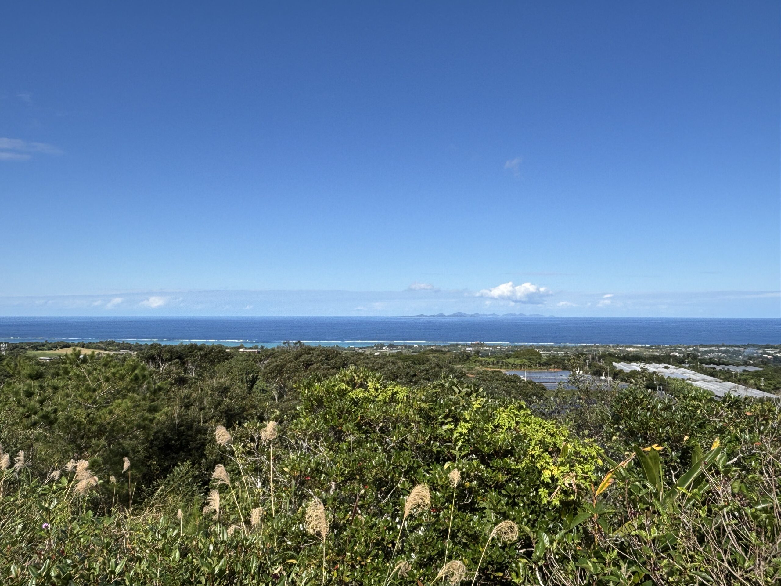 今帰仁の高台から見た海と空の風景。奥に島影が見える、晴れた日の景色。